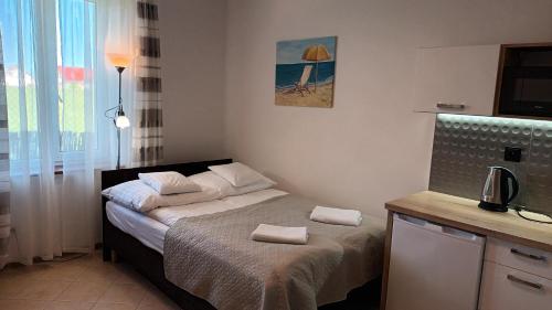 una piccola camera da letto con un letto e asciugamani di Pensjonacik Ewa a Darłowo