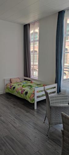 een slaapkamer met een bed, een stoel en een raam bij appartement du caractère in Elbeuf