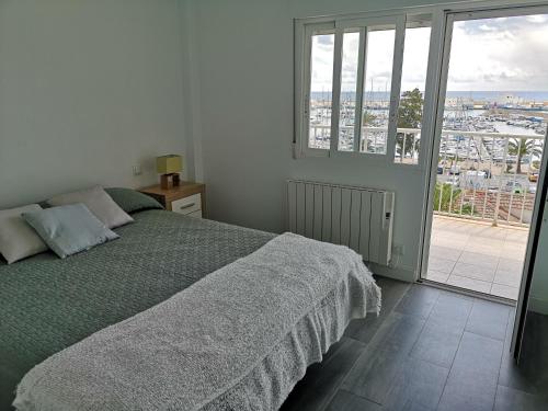 ein weißes Schlafzimmer mit einem Bett und einem großen Fenster in der Unterkunft Apartamento encantador con vistas al Club Naútico in Altea