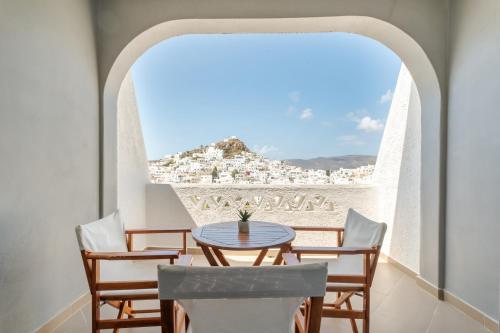 a table and chairs in a balcony with a view of a city at Sunrise Hotel in Ios Chora