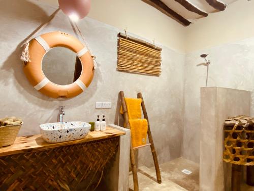 uma casa de banho com um lavatório e um espelho na parede em Mama Root em Kizimkazi