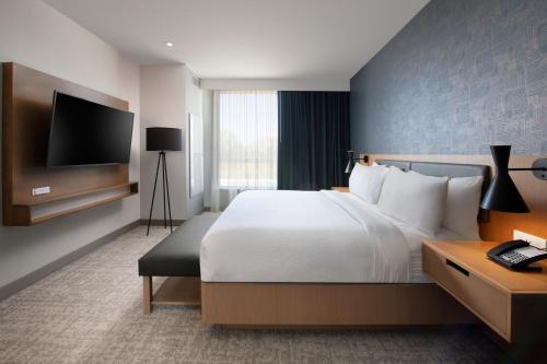 a hotel room with a bed and a flat screen tv at Residence Inn by Marriott St Louis Clayton in Clayton