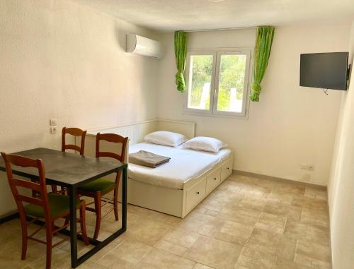 a bedroom with a bed and a table and a window at Studio Coin nuit 205 Résidence Les Acacias in Anduze