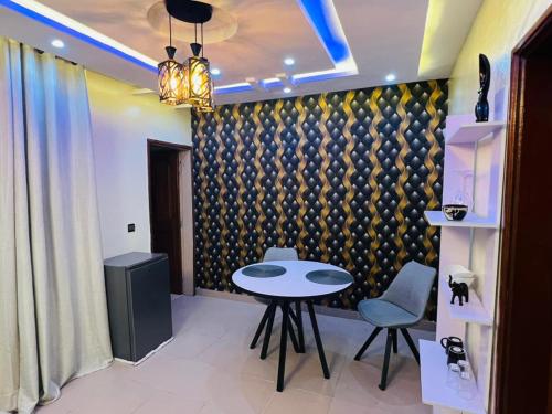a room with a table and two chairs and a wall at Apartment Diamant in Cotonou
