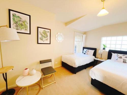 a bedroom with two beds and a table and a desk at Incredible Waterview - 4 Bedroom Hobart Waterside Cottage in Sandy Bay