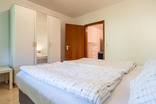 a white bedroom with two beds and a mirror at Appartement Langhammer in Tübingen