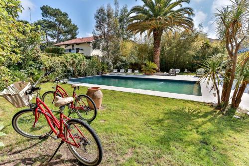 deux vélos garés dans l'herbe à côté d'une piscine dans l'établissement Embruns - Location vacances capbreton superbe villa avec jardin et piscine chauffée, à Capbreton