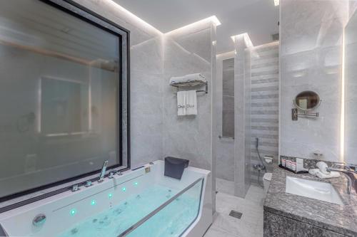 a bathroom with a large tub and a sink at Seven Gardens Hotel in Riyadh