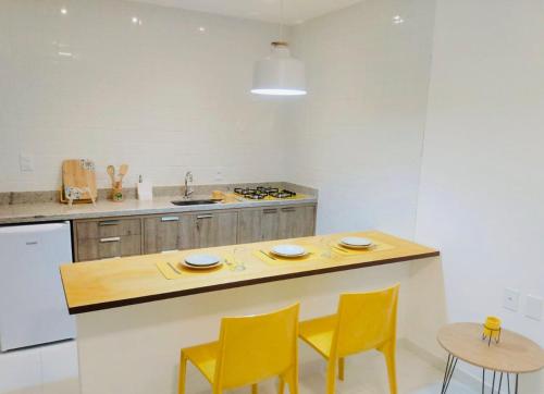 a kitchen with yellow chairs and a wooden counter top at Mar Turquesa Eco Pousada in Maragogi