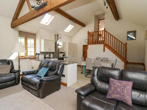 a living room with leather furniture and a kitchen at Bodnant in Tywyn