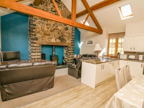 a kitchen and living room with a stone fireplace at Bodnant in Tywyn
