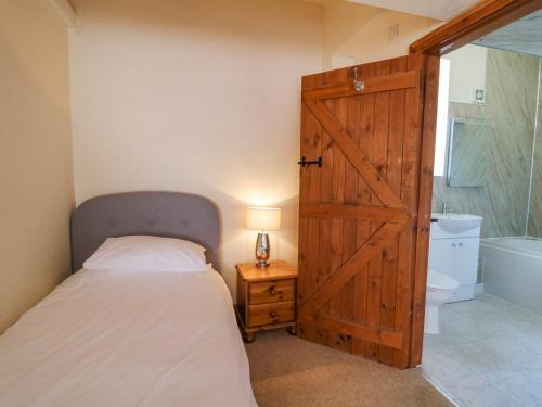 1 dormitorio con 1 cama y puerta de madera en Bodnant, en Tywyn