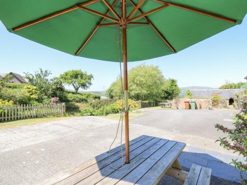 a green umbrella sitting on a wooden bench at Bodnant in Tywyn