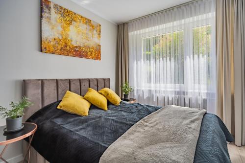 sypialnia z łóżkiem z żółtymi poduszkami i oknem w obiekcie Apartament Nova w Olsztynie