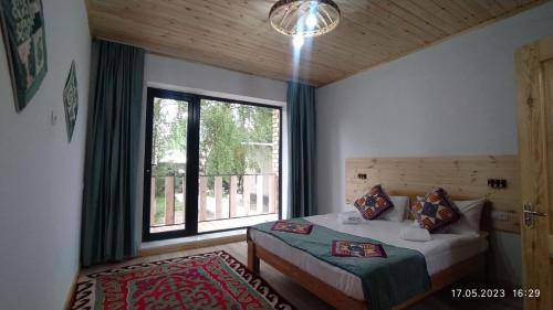 a bedroom with a bed and a large window at Guest House Jekshen in Imeni Karla Marksa