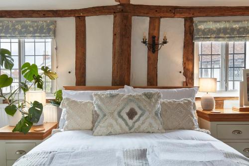 a bedroom with a bed with white sheets and windows at Copper Cottage in Clare in Sudbury