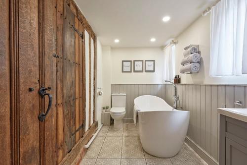 a bathroom with a tub and a toilet and a wooden door at Copper Cottage in Clare in Sudbury
