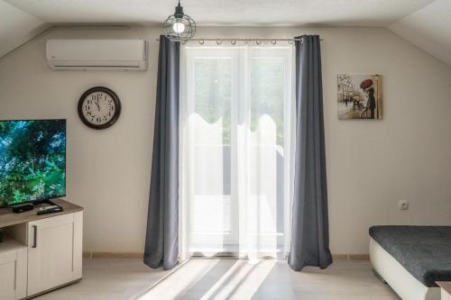 a bedroom with a large window and a clock at Holiday House Zrmanja Vrelo in Zrmanja Vrelo