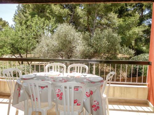 una mesa blanca y sillas en un balcón con árboles en Apartment Hameau de Provence by Interhome, en Bandol