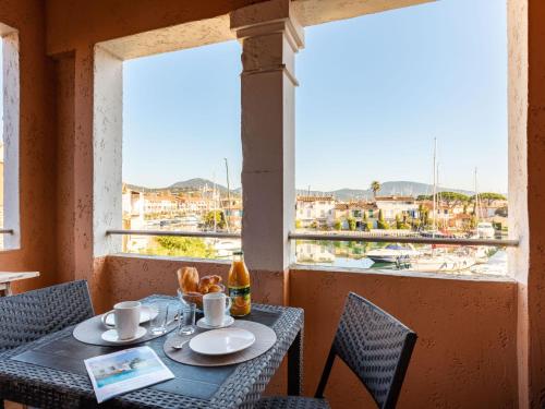 une table et des chaises avec vue sur une ville depuis une fenêtre dans l'établissement Apartment Grand Bassin by Interhome, à Grimaud