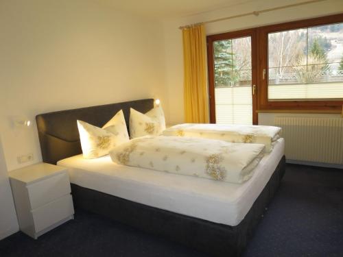 een slaapkamer met een bed met kussens en een raam bij Apartment Jordan by Interhome in Pettneu am Arlberg