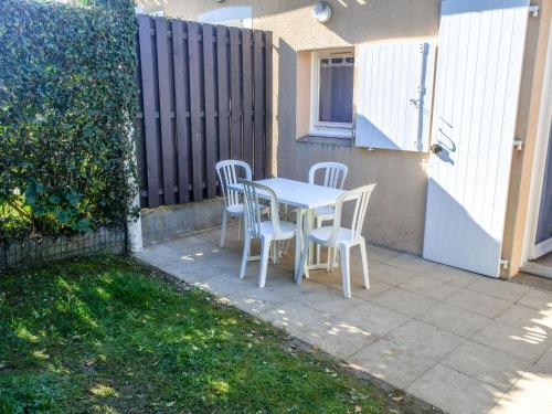 une table et des chaises sur une terrasse avec une clôture dans l'établissement Holiday Home Rivages d'Olonne by Interhome, à La Pironnière