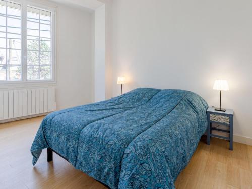a bedroom with a bed with a blue blanket on it at Apartment Le Manoir du Casino by Interhome in Cabourg