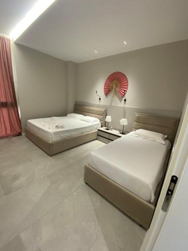 ヒマラにあるApartament Palase RREのベッドが2つあり、壁に赤い扇風機が取り付けられた寝室