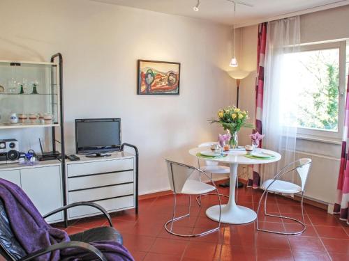een woonkamer met een tafel en stoelen en een televisie bij Apartment Cleopatra by Interhome in Montagnola