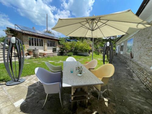 a table with chairs and an umbrella on a patio at Apartment Casa Vacanza Cascina Lovera-4 by Interhome in Belvedere Langhe