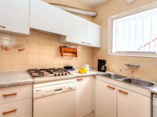cocina con armarios blancos, fregadero y ventana en Apartment Nicolas by Interhome, en Llançà
