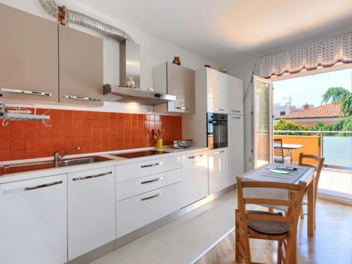 kuchnia z białymi szafkami i stołem oraz jadalnia w obiekcie Apartment Villa Alba-1 by Interhome w mieście Umag
