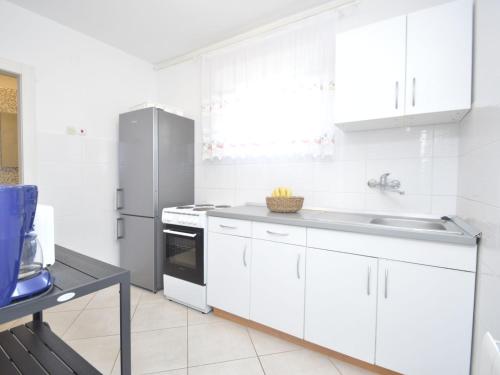 a kitchen with white cabinets and a stainless steel refrigerator at Apartment Bozac - PUL480 by Interhome in Šikići