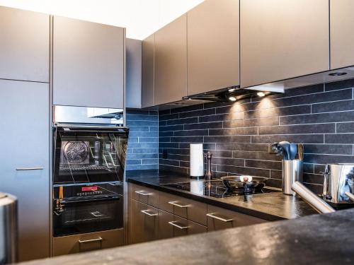 a kitchen with stainless steel appliances and blue tiles at Apartment TITLIS Resort 4-Zimmer Wohnung 12 by Interhome in Engelberg