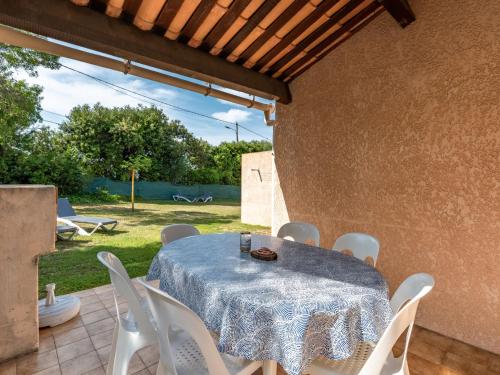 einen Tisch mit weißen Stühlen und einem blauen Tischtuch in der Unterkunft Holiday Home La Pinede - SAG171 by Interhome in Sagone