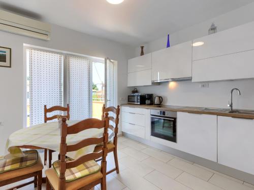 cocina con armarios blancos, mesa y sillas en Apartment Villa Alba-2 by Interhome, en Umag