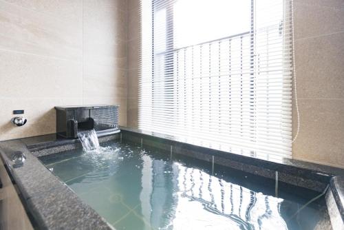 a pool of water in a bathroom with a window at Tokyu Stay Hakodate Asaichi Akarinoyu in Hakodate
