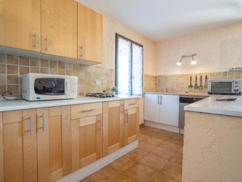 une grande cuisine avec des placards en bois et un four micro-ondes dans l'établissement Apartment Il était une fois-2 by Interhome, à Saint-Aygulf