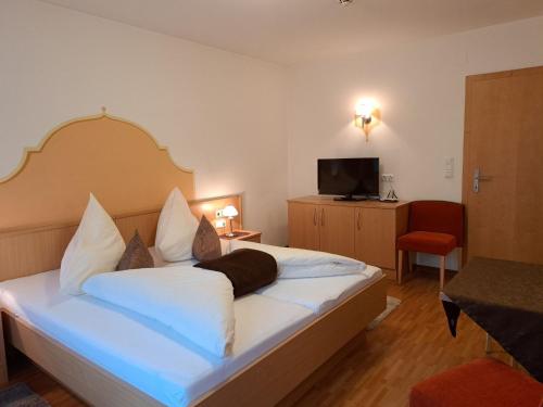 a bedroom with a large bed with white sheets and a television at Apartment Rosa-8 by Interhome in Mayrhofen