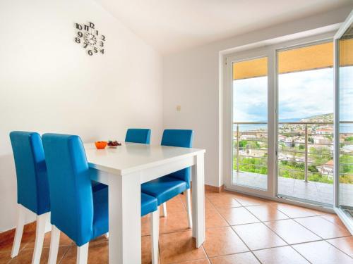 a dining room with a white table and blue chairs at Apartment Miškulin-1 by Interhome in Senj
