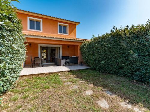 une maison orange avec un patio et une haie dans l'établissement Villa Gelormini-1 by Interhome, à Prunelli-di-Fiumorbo