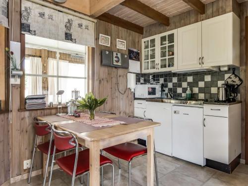 uma cozinha com armários brancos e uma mesa de madeira com cadeiras vermelhas em Holiday Home Djuvarp Ängen - SND117 by Interhome em Lekeryd