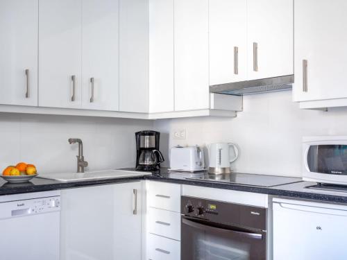 a white kitchen with white cabinets and a microwave at Apartment Atalaya Rio Verde by Interhome in Marbella