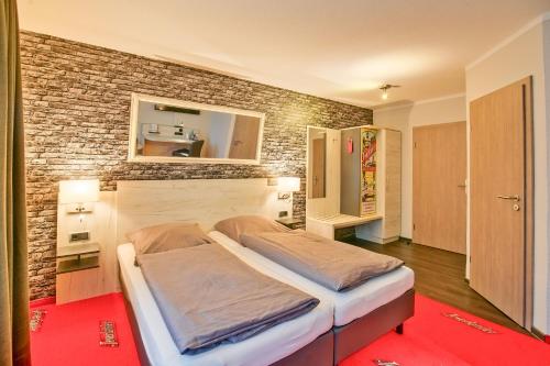 ein großes Bett in einem Zimmer mit Ziegelwand in der Unterkunft Hotel Im Schützenhof, Jever in Jever
