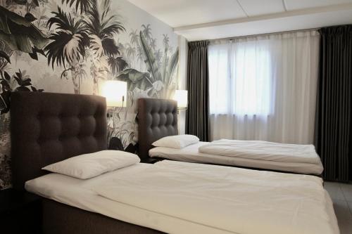 two beds in a hotel room with white sheets at Super Stay Hotel, Oslo in Oslo