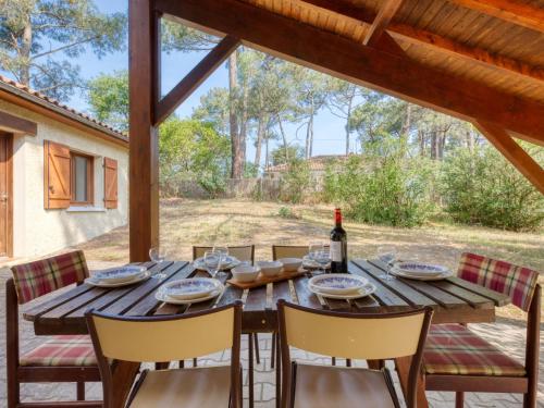 - une table en bois avec des chaises et une bouteille de vin dans l'établissement Holiday Home Club de la Voile by Interhome, à Le Moutchic
