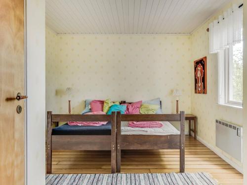 a bedroom with a wooden bed with colorful pillows at Holiday Home Ängasjö Ekbacken by Interhome in Östra Frölunda