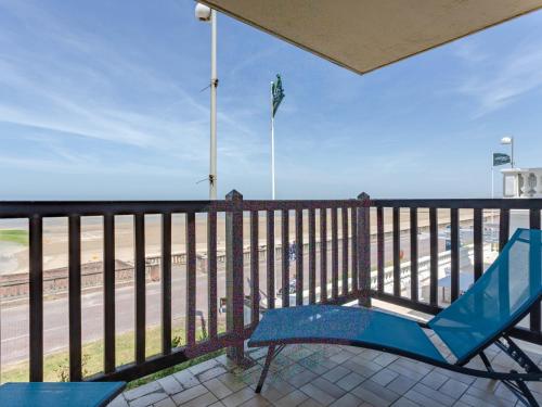 uma cadeira azul sentada numa varanda com vista para a praia em Apartment Les Terrasses du Casino by Interhome em Cabourg