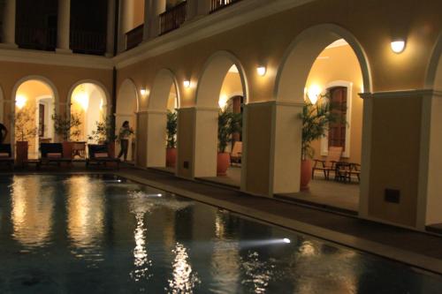 an indoor swimming pool in a building with lights at Palais De Mahe - A CGH Earth Experience in Puducherry