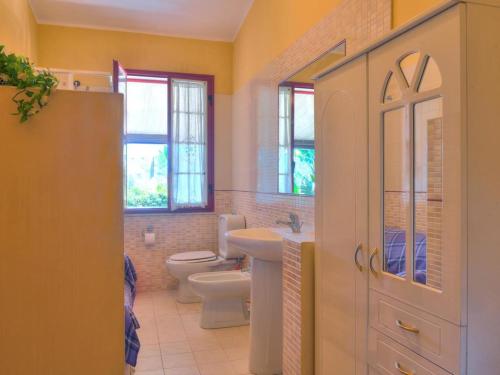 a bathroom with a sink and a toilet and windows at Villa Marianna by Interhome in Solarino